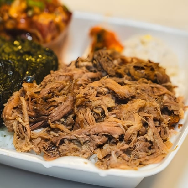 Close-up of a Hawaiian plate lunch with shredded kalua pig, rice, and green vegetables.